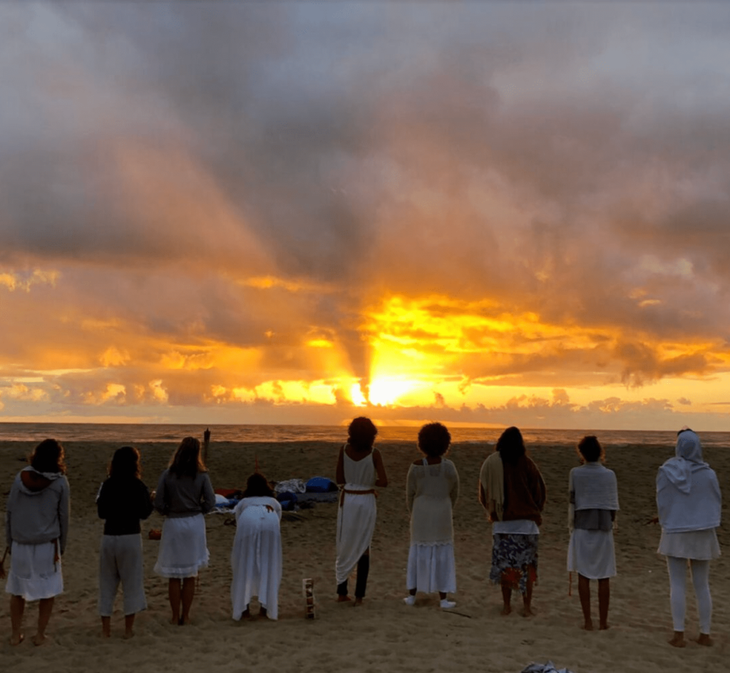 Group dressed in white watching the sunrise on Piracanga beach