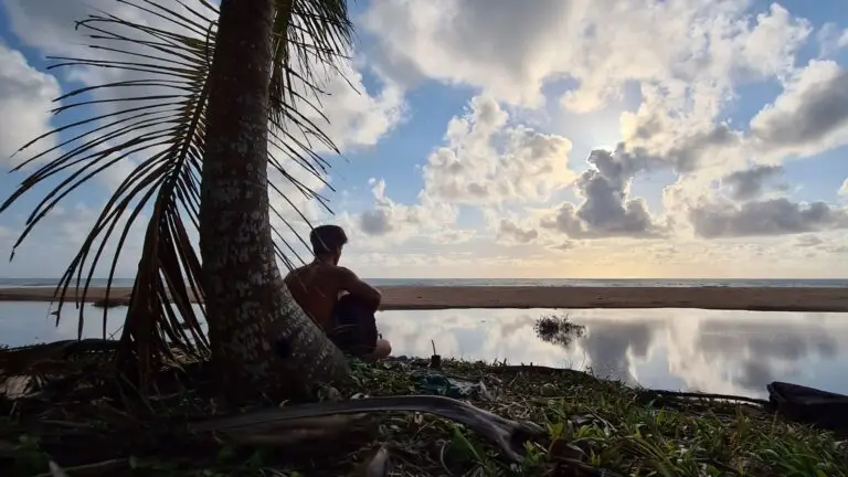 Blog Unah 10 Pessoa à sombra de um coqueiro contemplando o céu refletido na lagoa