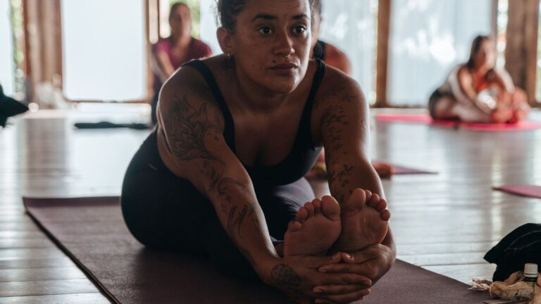 Blog Unah 8 Mulher em alongamento sentada no tapete durante prática de yoga