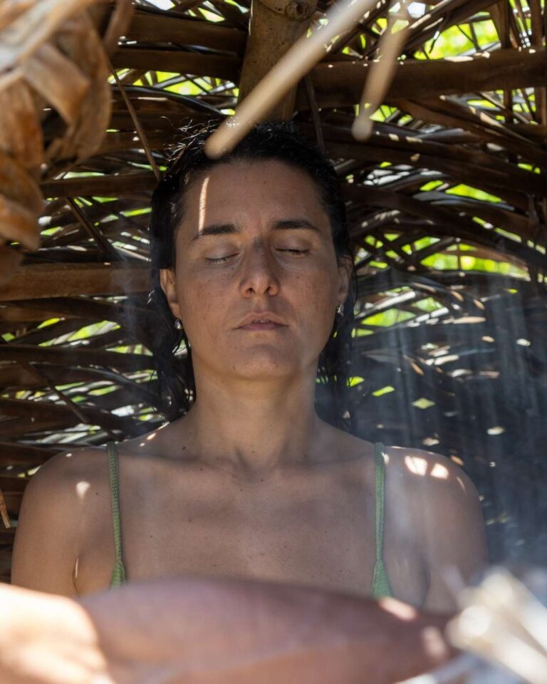 Mulher de olhos fechados em meditação sob estrutura de bambu