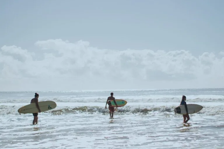 Participantes do Ayáma entrando no mar com pranchas de surf em Piracanga