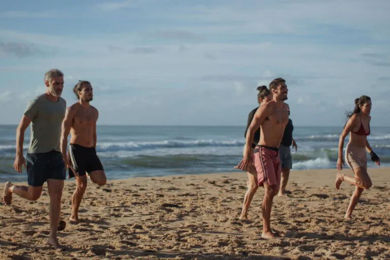 Participantes do retiro Ayáma correndo na areia da praia de Piracanga