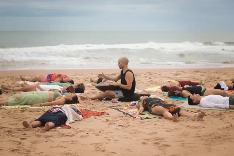Participantes da Imersão Unah deitados na areia em prática de meditação com som de handpan na praia de Piracanga
