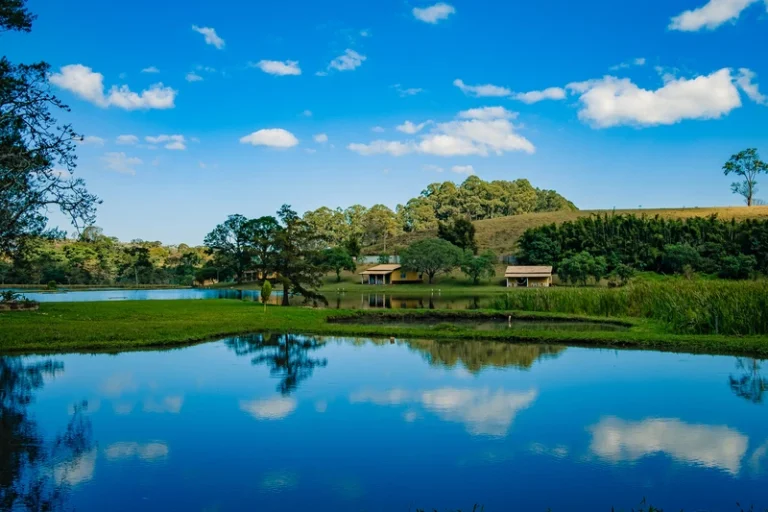 Lago espelhando o céu azul no local do Respiro Unah, em Joanópolis, na Serra da Mantiqueira