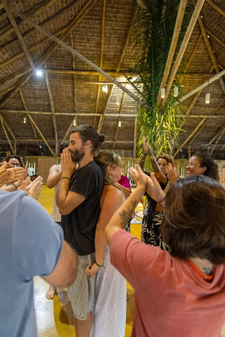 Participantes de retiro em roda com as mãos postas numa oca de Unah