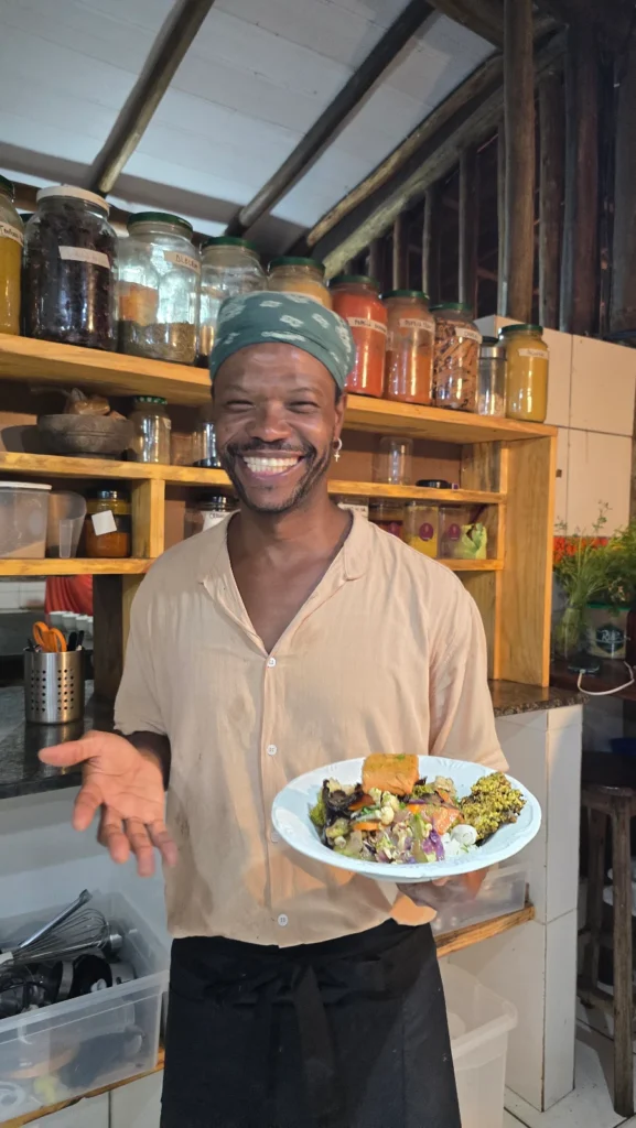 Cozinheiro do Karuh sorrindo com um prato vegano na cozinha do restaurante