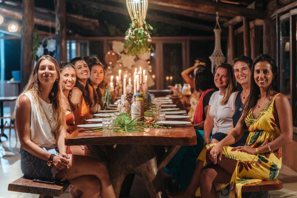 Participantes sentados juntos na mesa coletiva do Karuh, decorada com velas e plantas