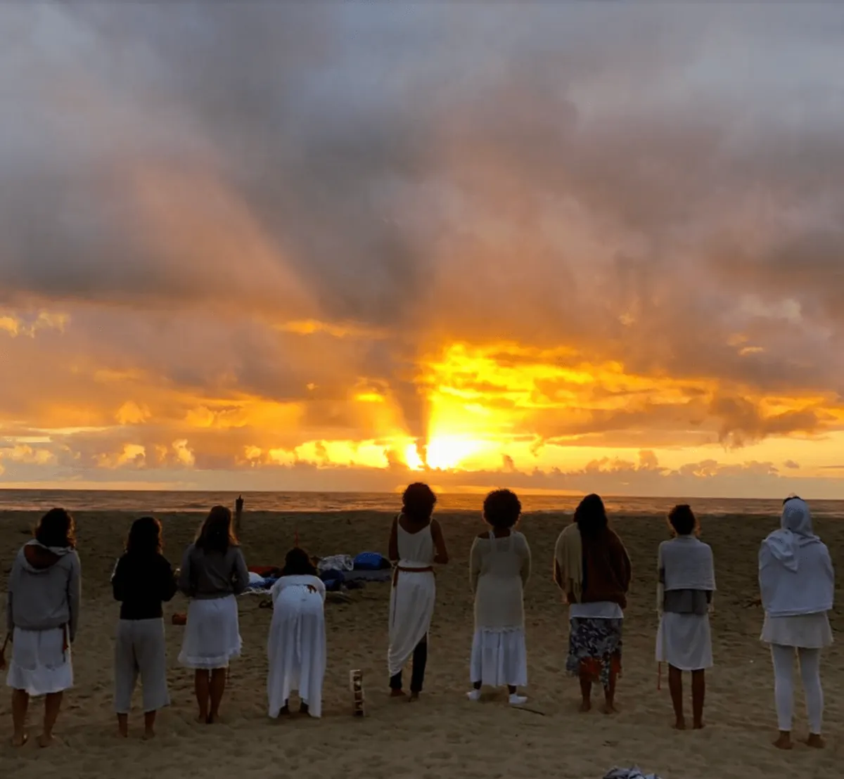 Group dressed in white watching the sunrise on Piracanga beach
