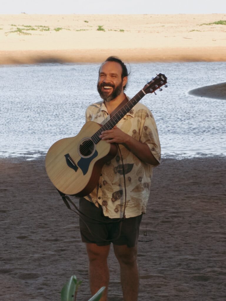 Vinícius Barros, facilitador do Retiro Renascer, com violão à beira do rio Piracanga
