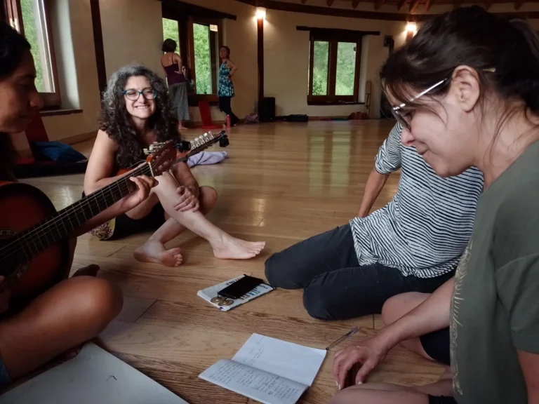Participantes cantando com violão e cadernos em roda no chão