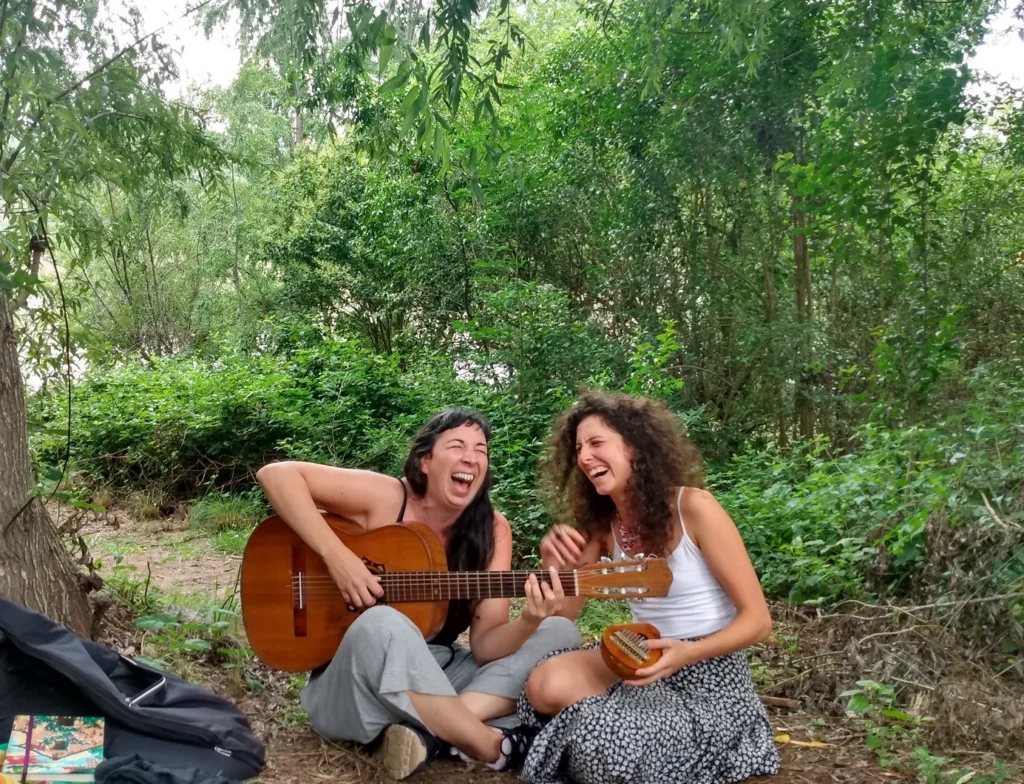 Duas cantoras cantando com violão em meio à floresta