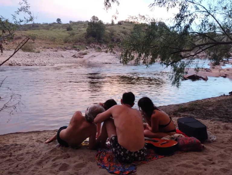 Participantes reunidos à beira do rio ao entardecer, retiro de canto Todas las voces son del agua