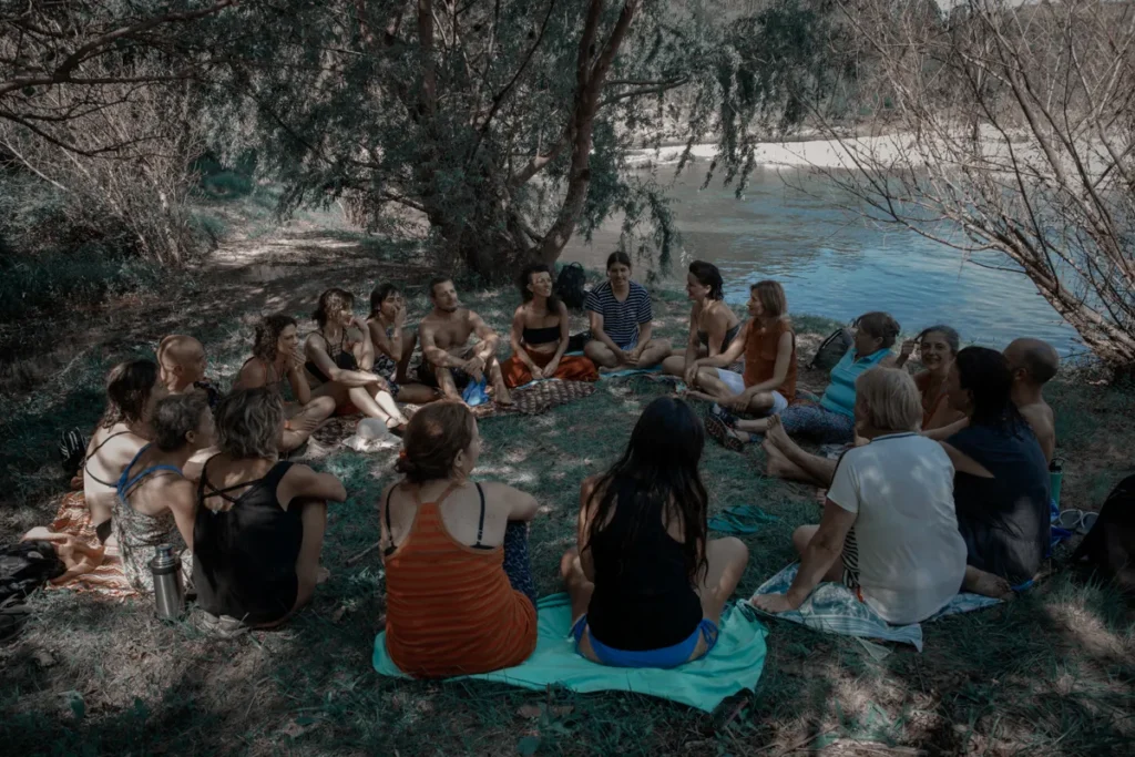 Roda de canto ao ar livre à beira do rio, entre árvores