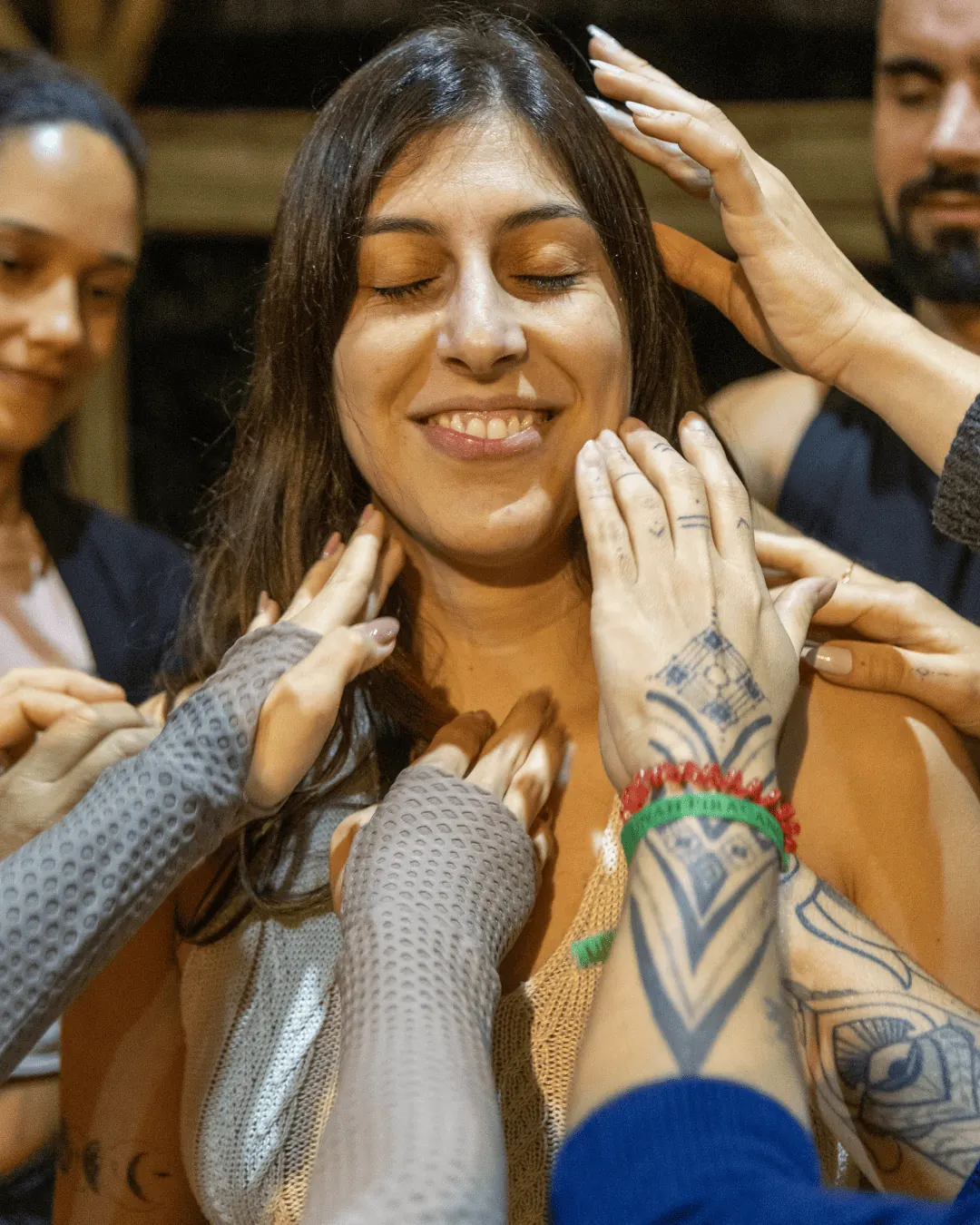 Participante sorridente recebe toque acolhedor do grupo em retiro de autoconhecimento