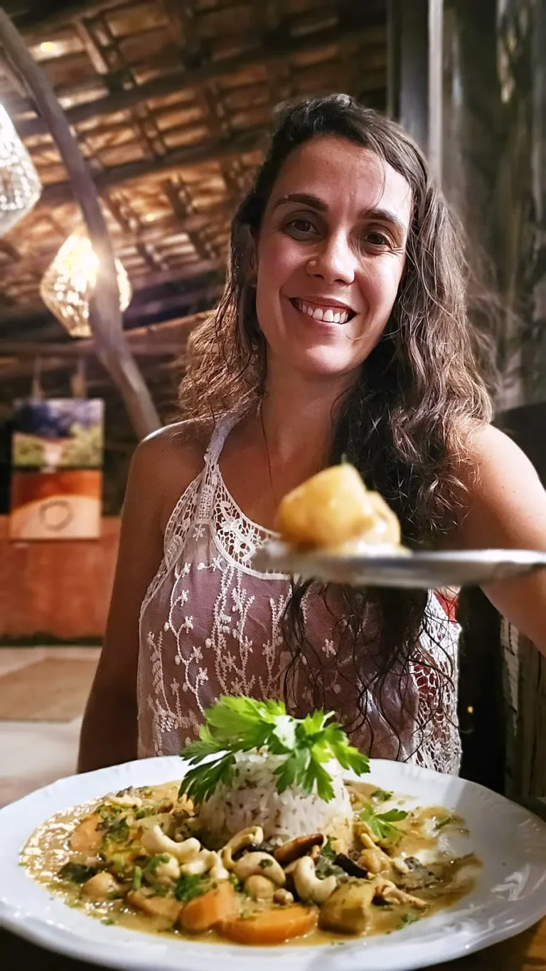 Visitante sorridente com prato vegano e sobremesa no salão do Karuh