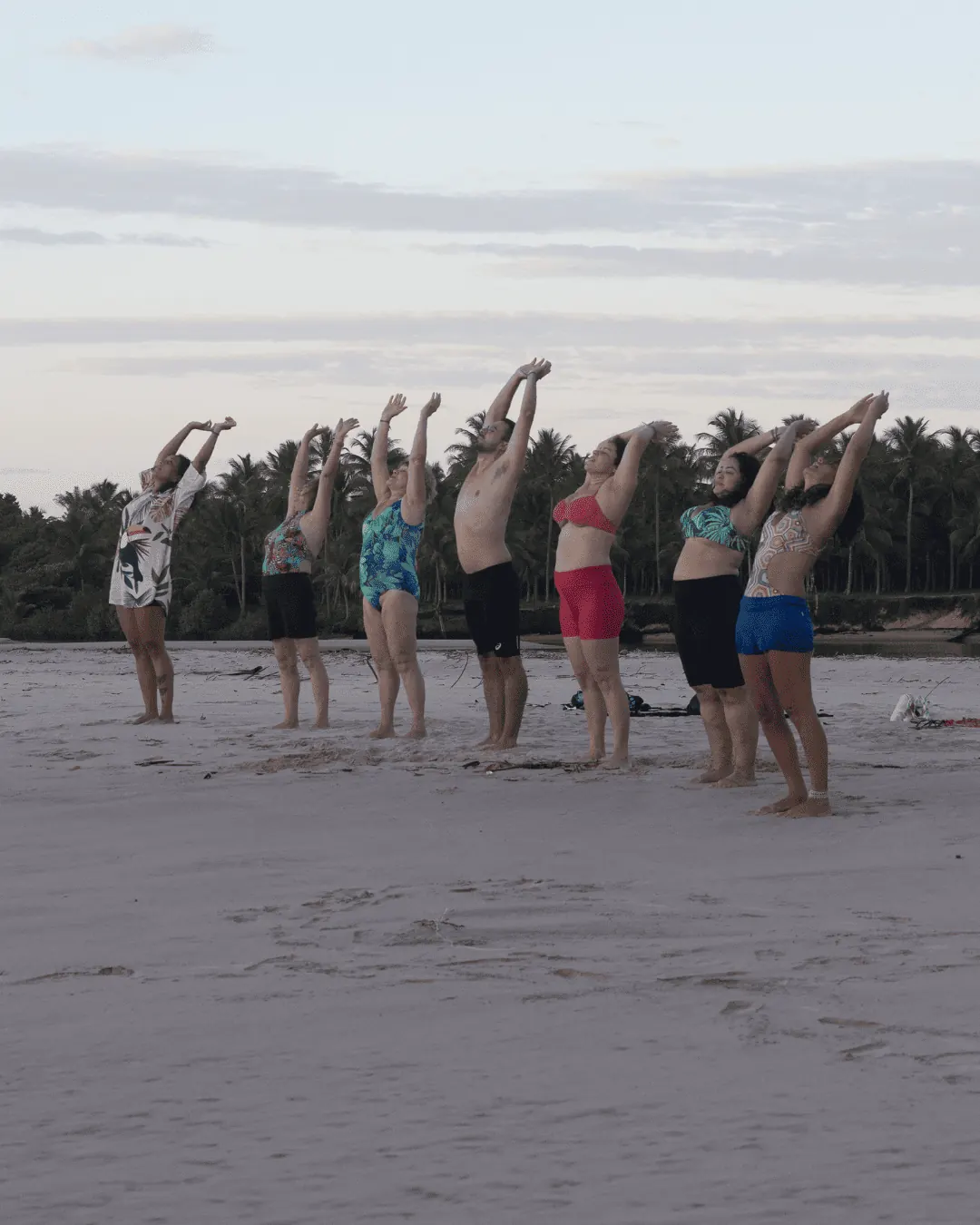 Grupo pratica yoga ao entardecer na praia de Piracanga